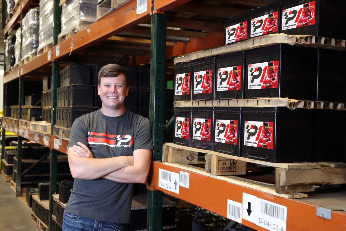 Erik Jones leans against warehouse battery rack wit P1 Batteries